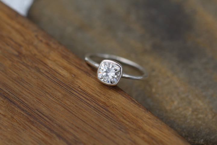 Colorless Moissanite 6x6mm Cushion Cut Bezel Solitaire Ring With A Medium/Lightweight Band Sennin Esko Jewelry Alternative Engageme, Dainty Band, Dainty Moissanite, Ethical Engagement, Forever One Ring, Gold Moi FINE RINGS / ENGAGEMENT